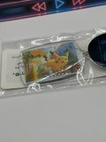 A Pokémon Pikachu acrylic keychain in its clear plastic packaging, featuring a printed illustration of Pikachu on a silver-toned rectangular case with a black metal keyring.