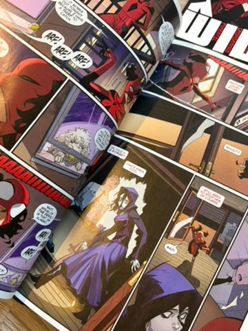 An open comic book or graphic novel spread, showing multiple illustrated panels with a red-and-black spider-themed character and a purple-robed figure in a room scene.