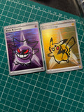 Two Pokémon Energy cards laid on a green cutting mat: Gengar on the left with a purple background, and Pikachu on the right with a gold background.