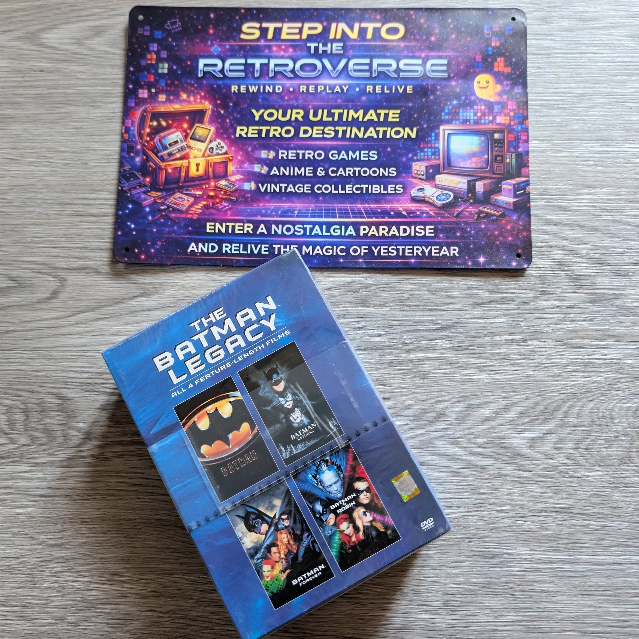 Two product boxes on a wooden surface, one labeled 'The Batman Legacy' and the other 'Step into the Retroverse'.
