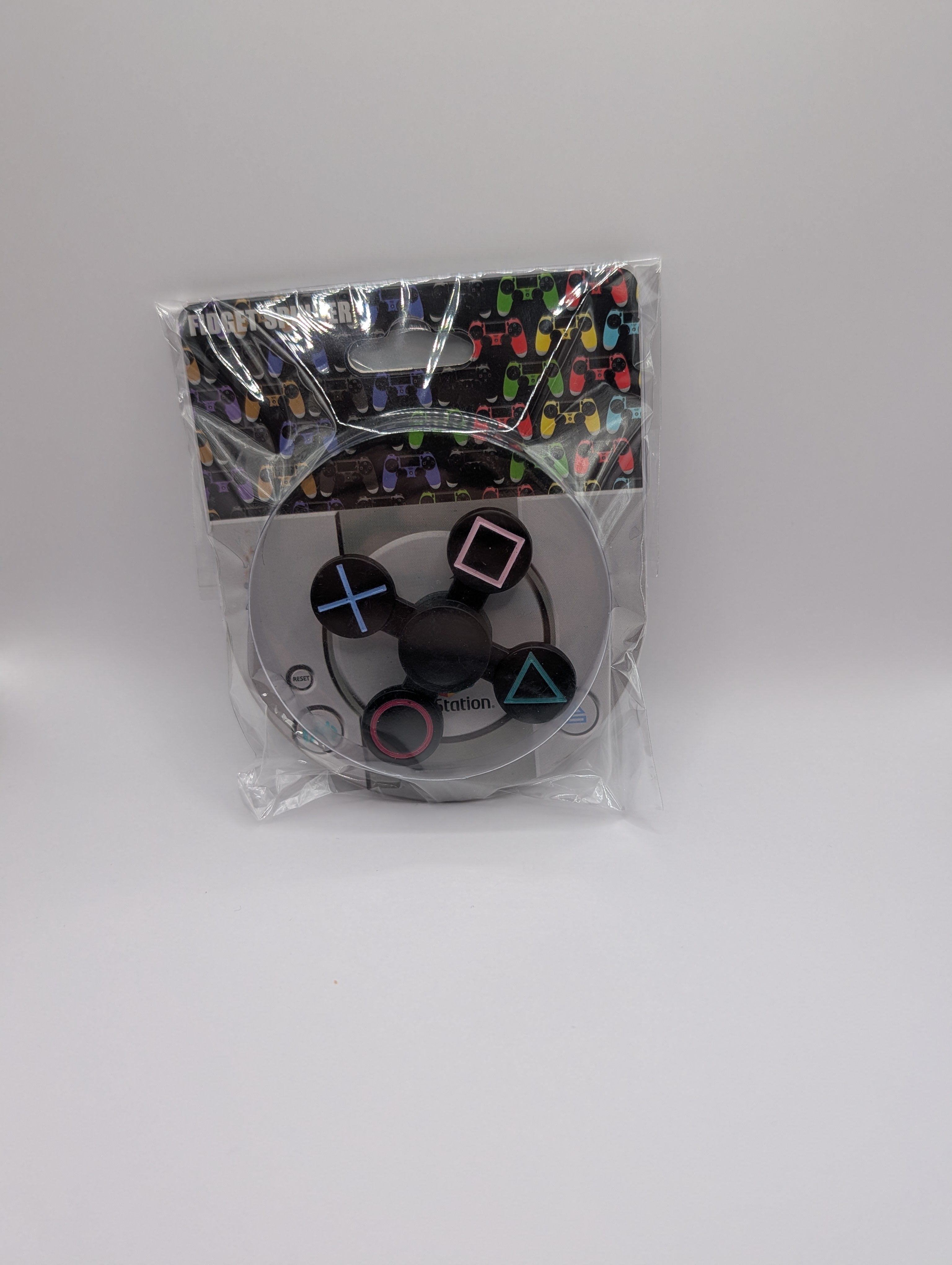 Packaged gaming controller with colorful symbols on a white background